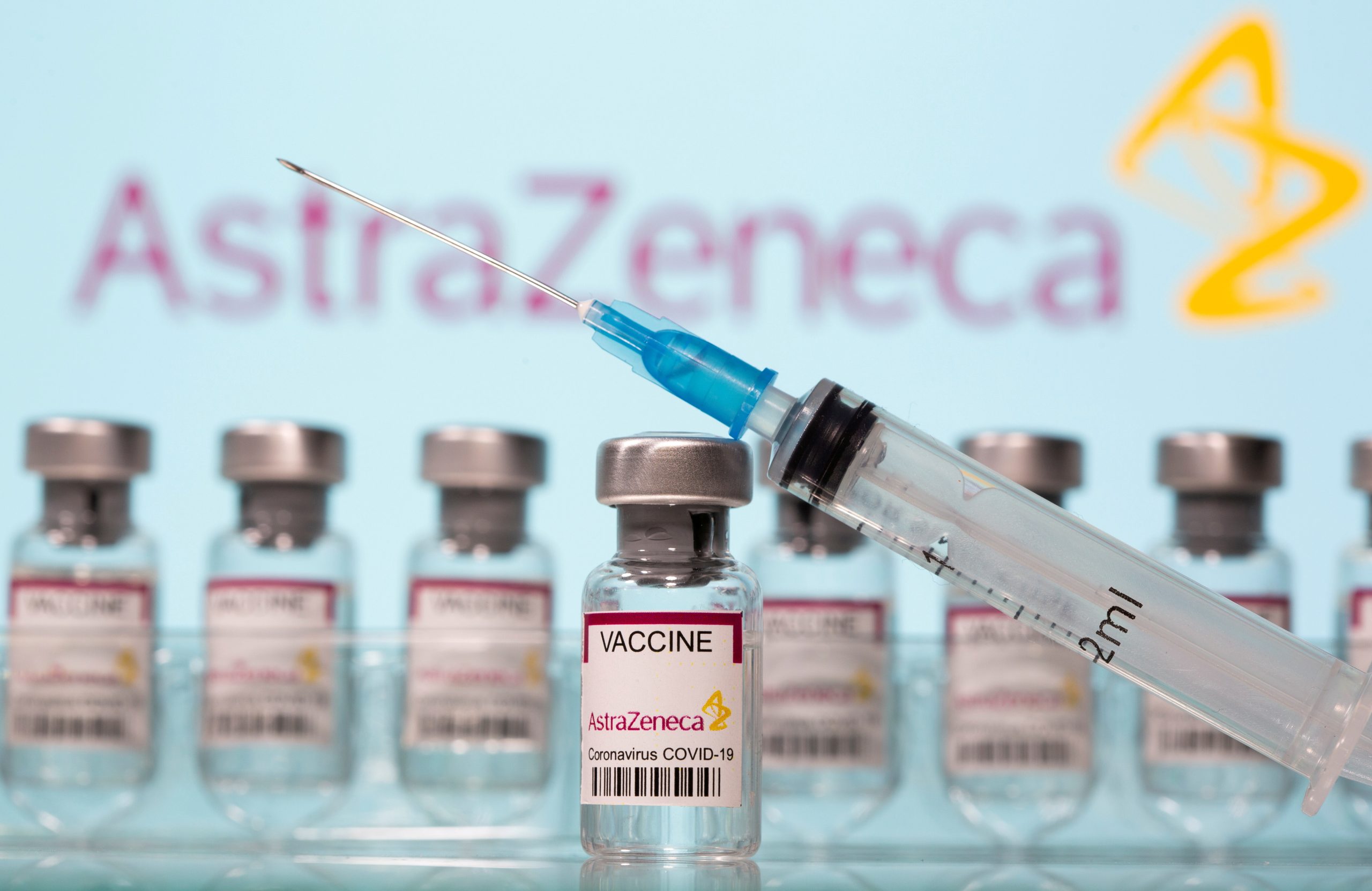 FILE PHOTO: Vials labelled “AstraZeneca COVID-19 Coronavirus Vaccine” and a syringe are seen in front of a displayed AstraZeneca logo